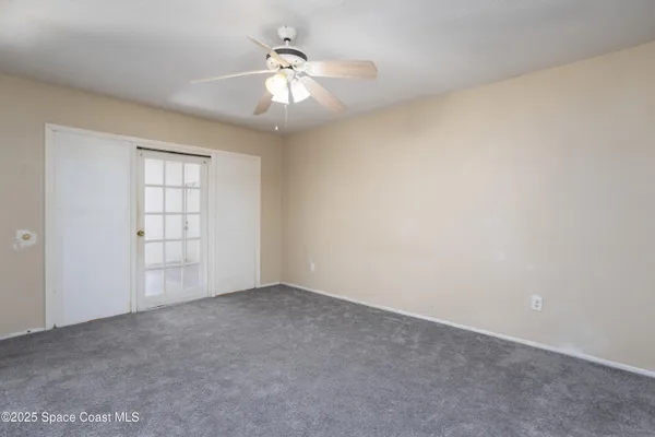 an empty room with windows and chandelier fan