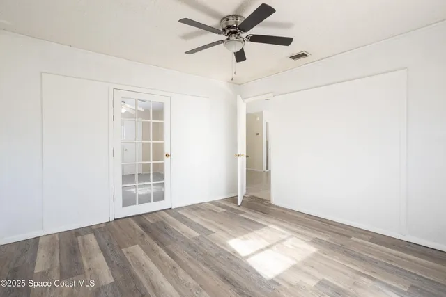 an empty room with wooden floor ceiling fan and windows