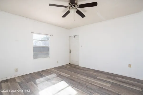an empty room with a ceiling fan and windows