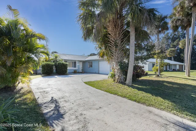 a view of a house with a yard and coconut trees