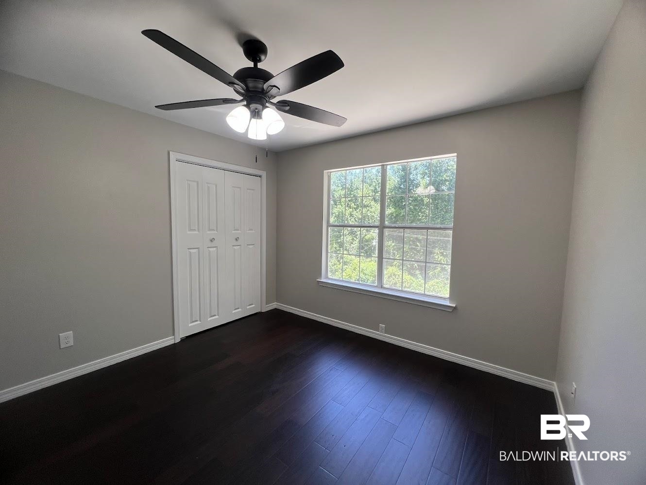266 Ridgewood Drive Daphne, AL 36526 - Photo 17 of 34 Spacious room featuring dark wood-finish flooring, a large window, a modern ceiling fan with integrated lighting, and neutral wall tones