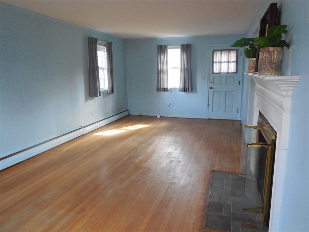 108 West Meadowview Road Holyoke, MA 01040 - Photo 4 of 18 an empty room with wooden floor a fireplace and windows