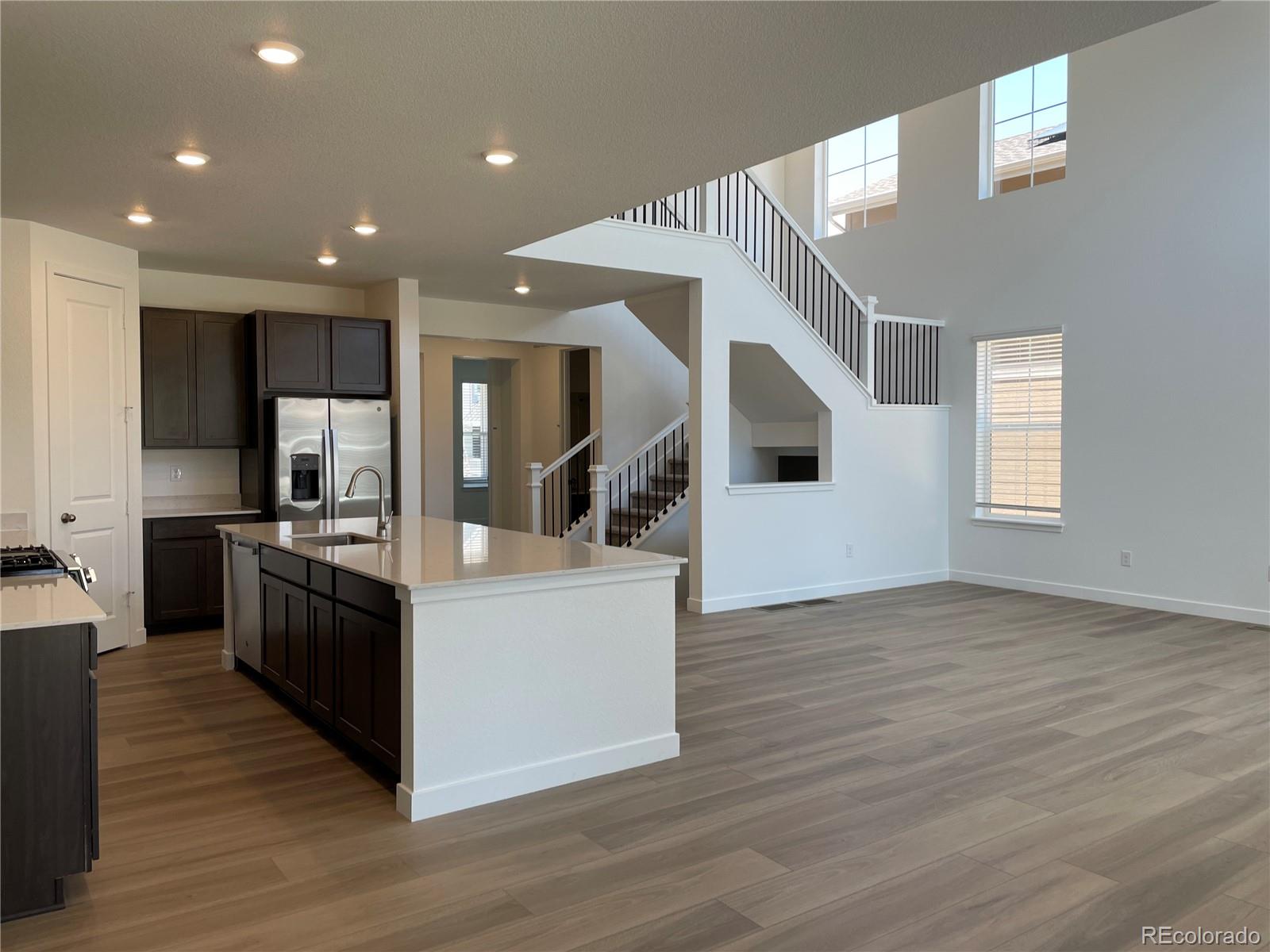 4598 Windmill Drive Brighton, CO 80601 - Photo 2 of 21 a kitchen with stainless steel appliances kitchen island wooden floors and white cabinets