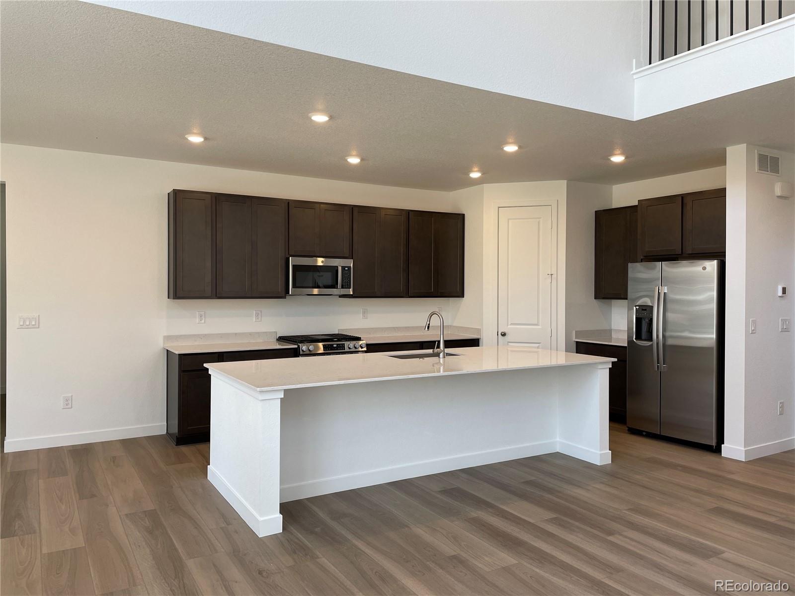 4598 Windmill Drive Brighton, CO 80601 - Photo 3 of 21 a kitchen with stainless steel appliances granite countertop a refrigerator a stove top oven a sink and dishwasher with wooden floor