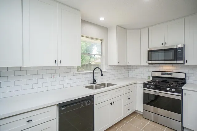 a kitchen with white cabinets a sink stove and refrigerator