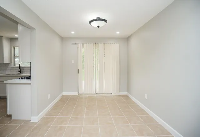 a view of an empty room with wooden floor and a ceiling fan