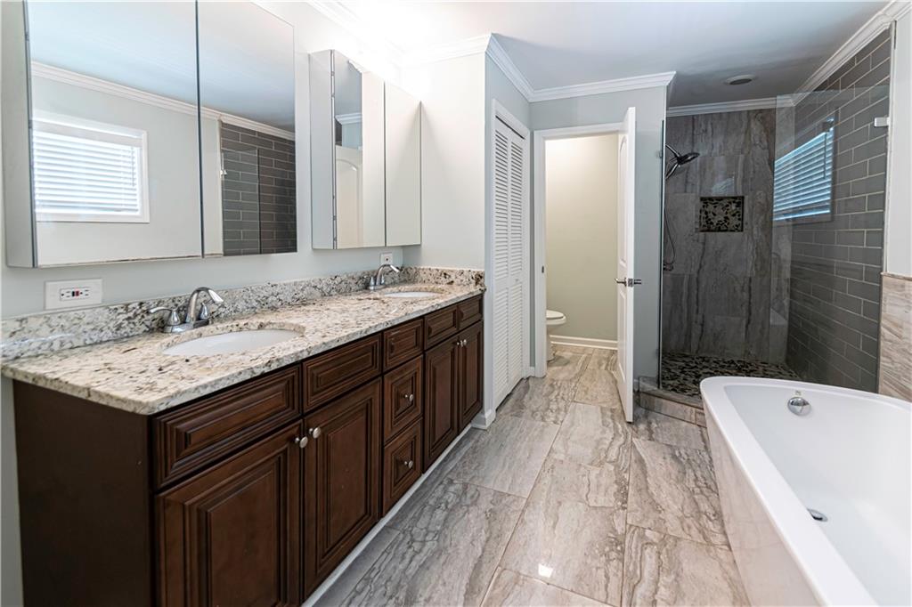 1892 Terry Mill Road Southeast Atlanta, GA 30316 - Photo 16 of 25 a spacious bathroom with a granite countertop sink a toilet a mirror a shower and a bathtub
