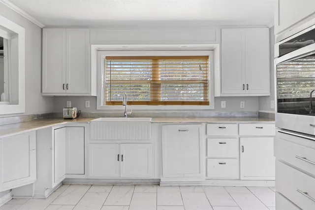 a kitchen with white cabinets appliances a sink and a window