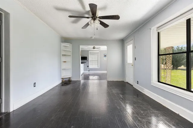 a view of an empty room with a window and wooden floor