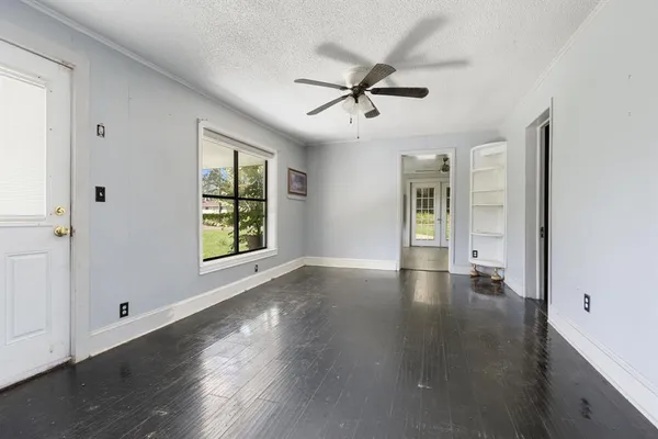 a view of an empty room with wooden floor and a window