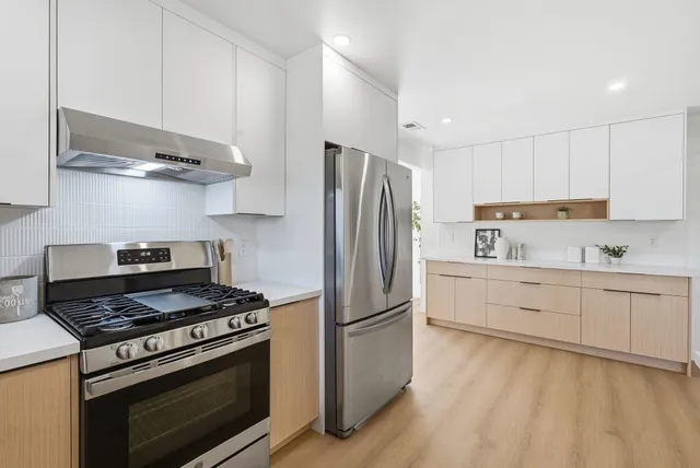 a kitchen with stainless steel appliances white cabinets and a stove top oven