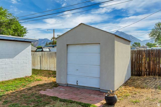 730 Geranium Street Sandy, UT 84094 - Photo 24 of 35 Detached storage building featuring a roll-up door, stucco exterior, and red brick paver pad