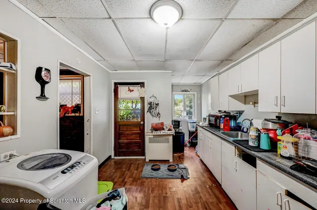 a kitchen with stainless steel appliances granite countertop a refrigerator a sink dishwasher and white cabinets with wooden floor