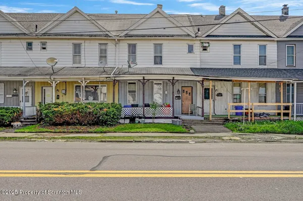 a front view of a house with a yard and potted plants