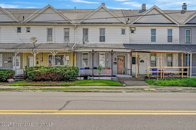 a front view of a house with a yard and potted plants