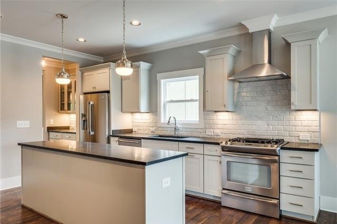 a kitchen with granite countertop stainless steel appliances a stove and a wooden floor
