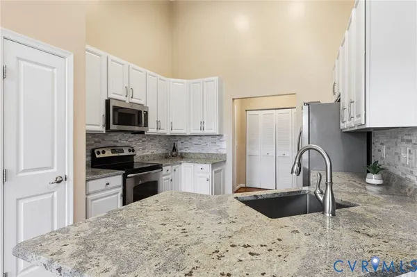 a kitchen with granite countertop a stove a sink and a microwave