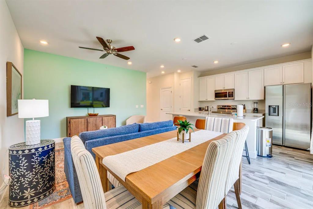 8209 Surf Street Kissimmee, FL 34747 - Photo 5 of 74 a kitchen with stainless steel appliances kitchen island granite countertop a refrigerator a stove top oven a sink with island and chairs