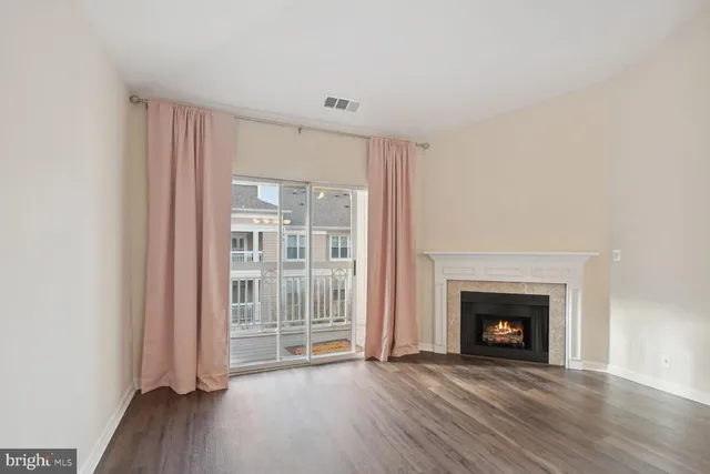 an empty room with wooden floor fireplace and windows