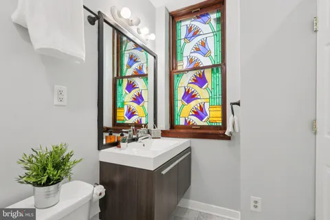 a bathroom with a sink a painting on the wall and a shower curtain