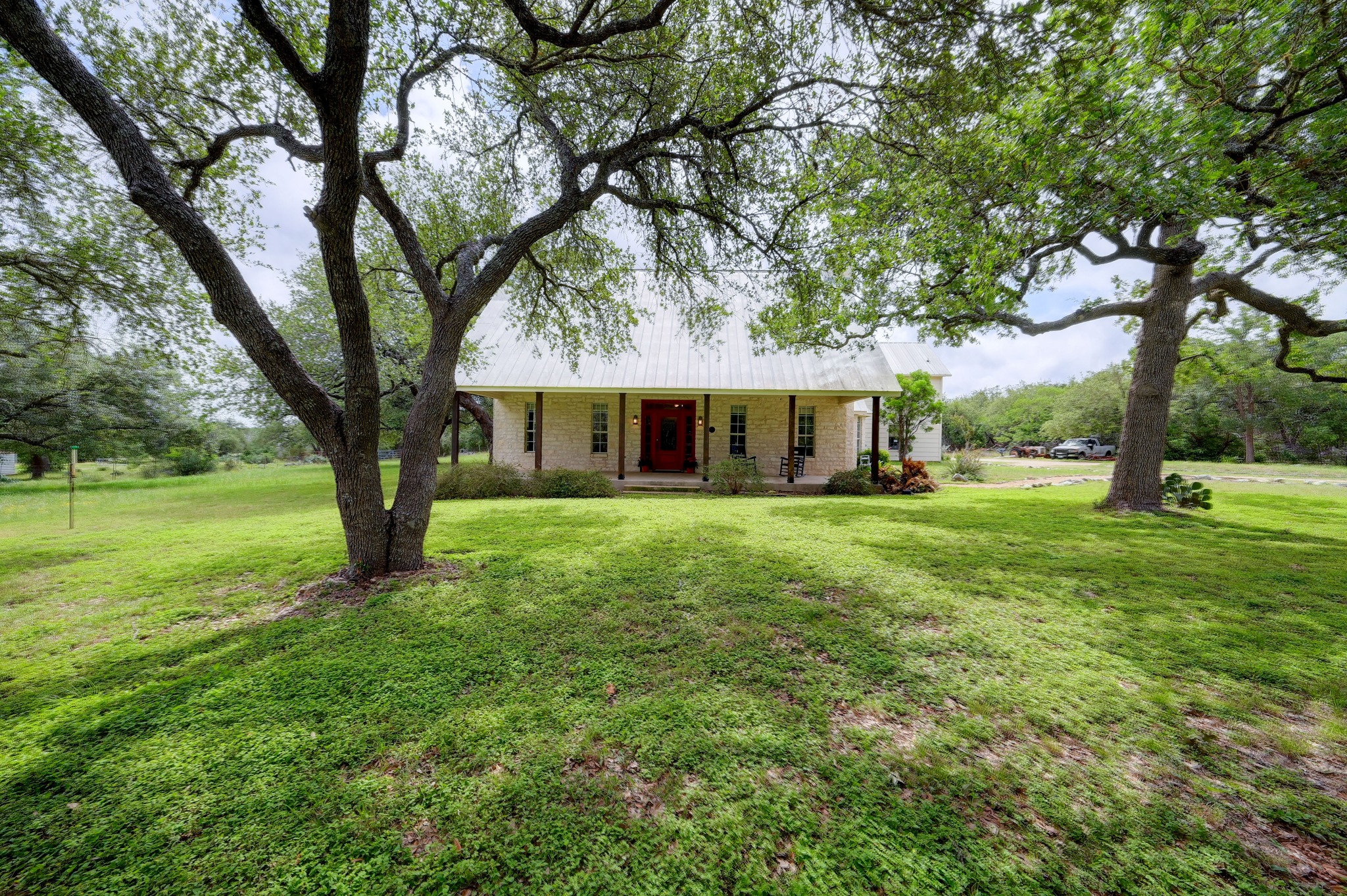 364 Nameless Road Driftwood, TX 78619 - Photo 5 of 32 Mature trees shade this charming home, boasting a metal roof and inviting covered porch.