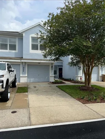 a view of a white house with a large tree