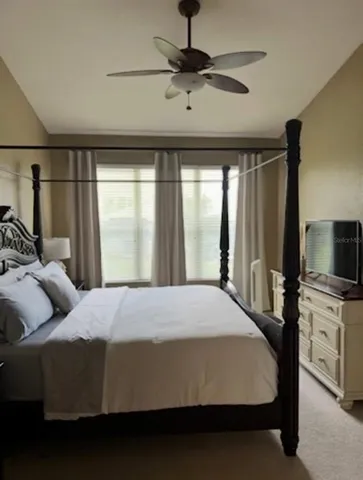 a bedroom with a bed flat screen tv and a large window