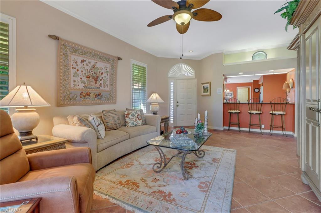 11745 Quail Village Way Naples, FL 34119 - Photo 4 of 24 Living room with light tile patterned flooring, ornamental molding, and ceiling fan