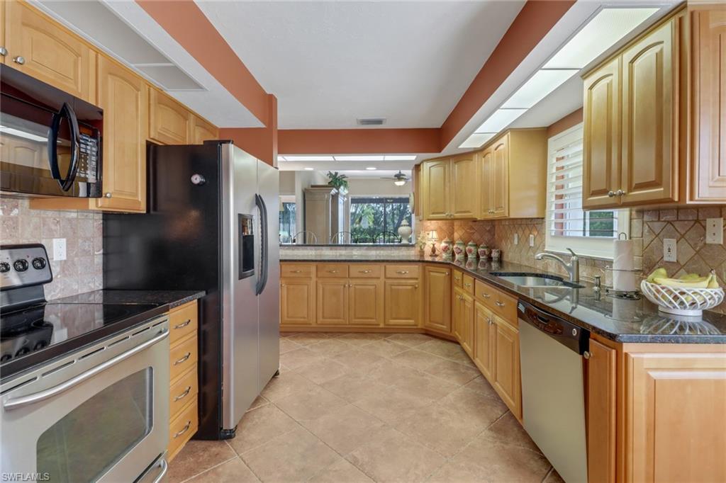 11745 Quail Village Way Naples, FL 34119 - Photo 5 of 24 Kitchen with light tile patterned flooring, backsplash, stainless steel appliances, dark stone counters, and sink