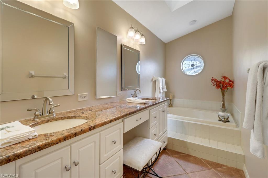 11745 Quail Village Way Naples, FL 34119 - Photo 8 of 24 Bathroom featuring vanity, vaulted ceiling, tile patterned floors, and a relaxing tiled tub