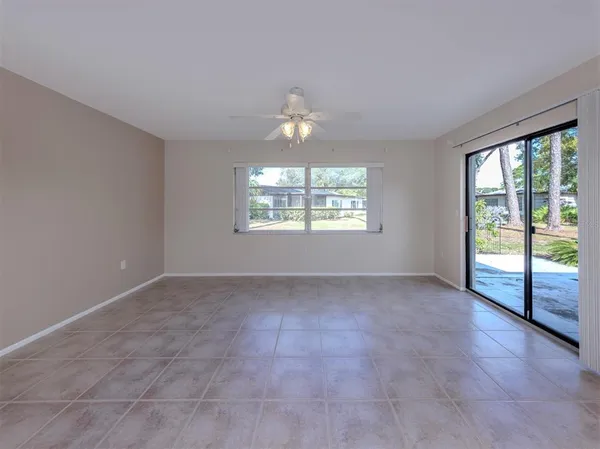 an empty room with chandelier fan and windows