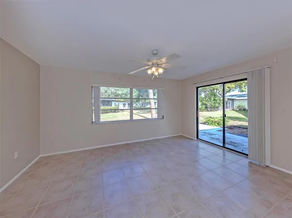 an empty room with chandelier fan and windows