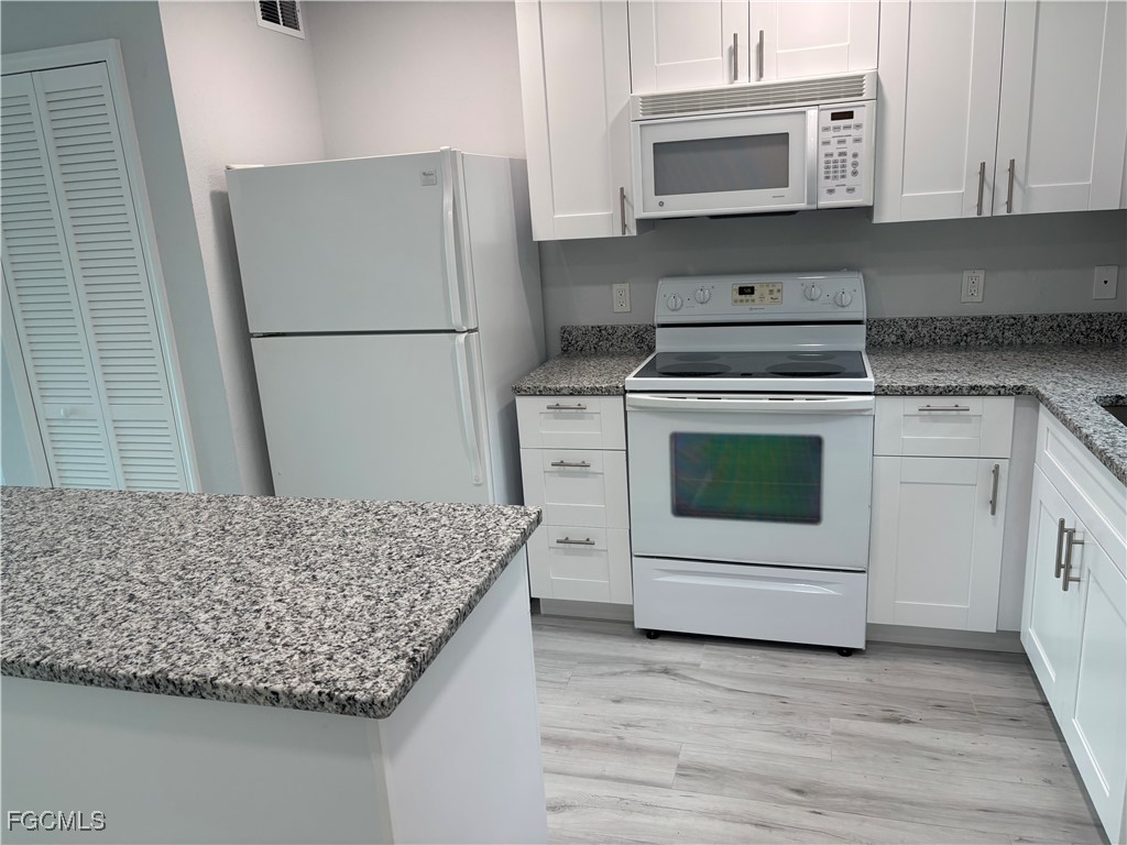 16881 Davis Road, Unit 414 Fort Myers, FL 33908 - Photo 6 of 24 a kitchen with granite countertop white cabinets and white appliances