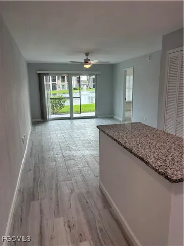 a kitchen with stainless steel appliances granite countertop a refrigerator a sink a stove and white cabinets with wooden floor