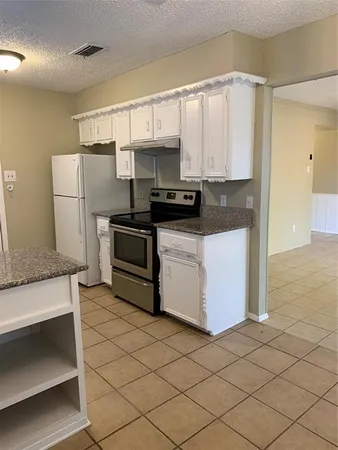 a kitchen with stainless steel appliances a refrigerator a sink and white cabinets
