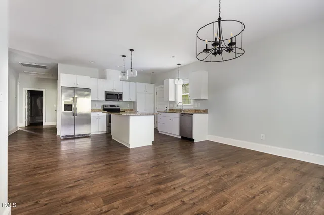 a kitchen with stainless steel appliances granite countertop a sink a stove a refrigerator cabinets and living room view