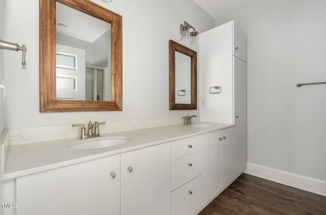 a bedroom with a large bed a flat screen tv on dresser and a chandelier