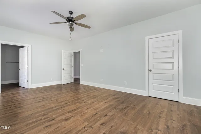 an empty room with wooden floor fan and windows