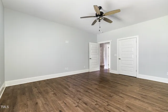 an empty room with wooden floor ceiling fan and windows