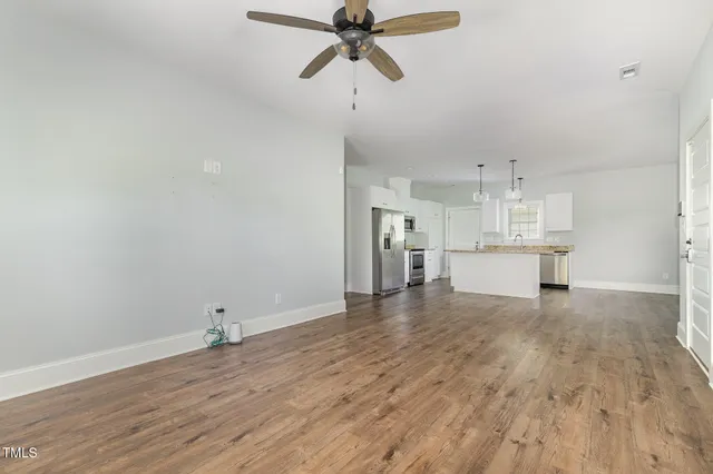 a view of kitchen and empty room with wooden floor
