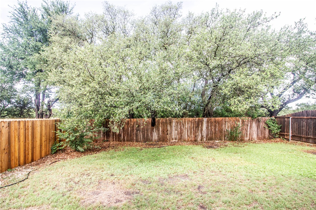 413 Moorhen Cove Leander, TX 78641 - Photo 18 of 18 a view of a backyard with large tree and wooden fence