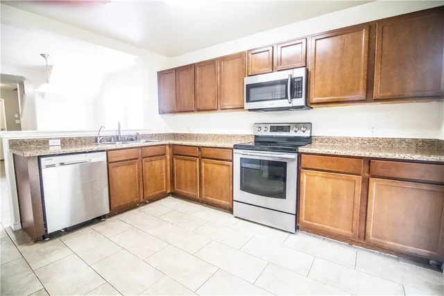 a kitchen with stainless steel appliances granite countertop a stove top oven a sink dishwasher and white cabinets