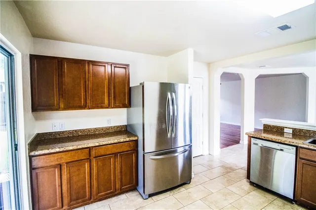 a kitchen with granite countertop a refrigerator and a stove top oven