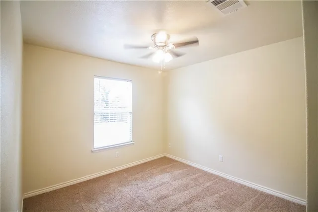 an empty room with a window and a fan
