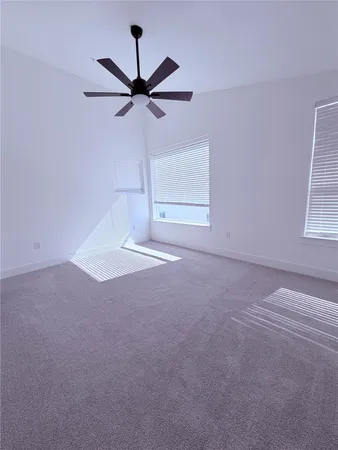a view of a big room with a ceiling fan and windows