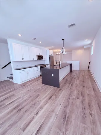 a large room with kitchen island a wooden floor and a sink