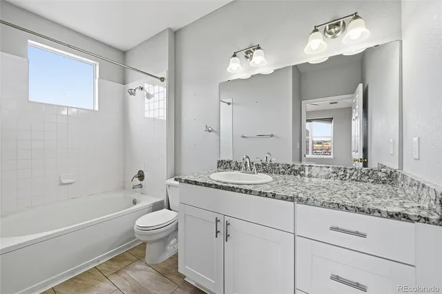 a bathroom with a granite countertop sink a toilet and bathtub