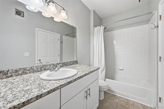 a bathroom with a granite countertop sink a toilet and shower