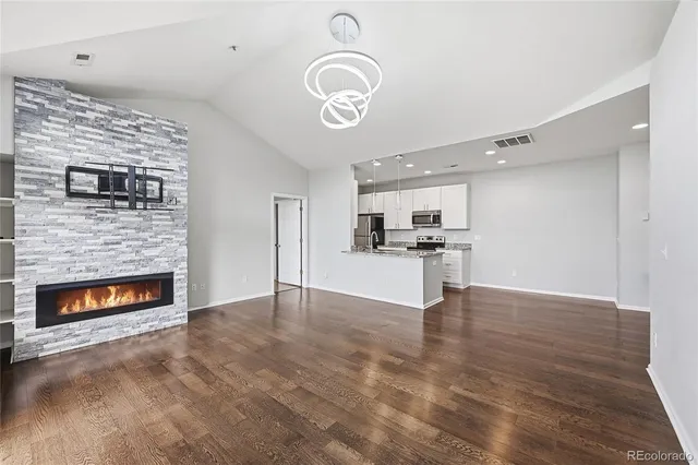 a view of empty room with kitchen and fireplace