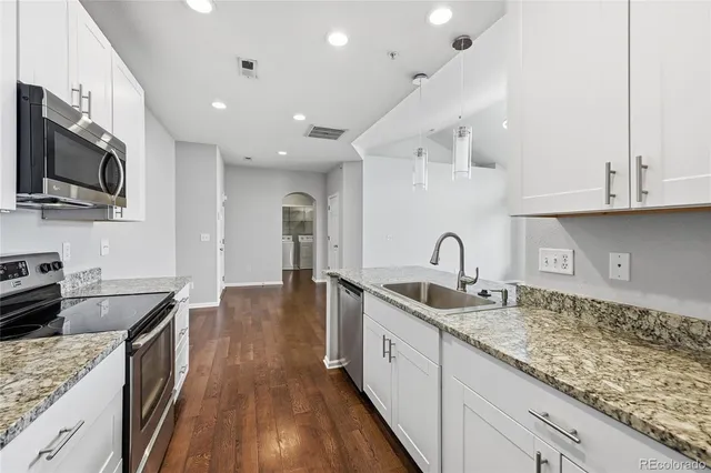 a kitchen with granite countertop a sink stainless steel appliances and cabinets